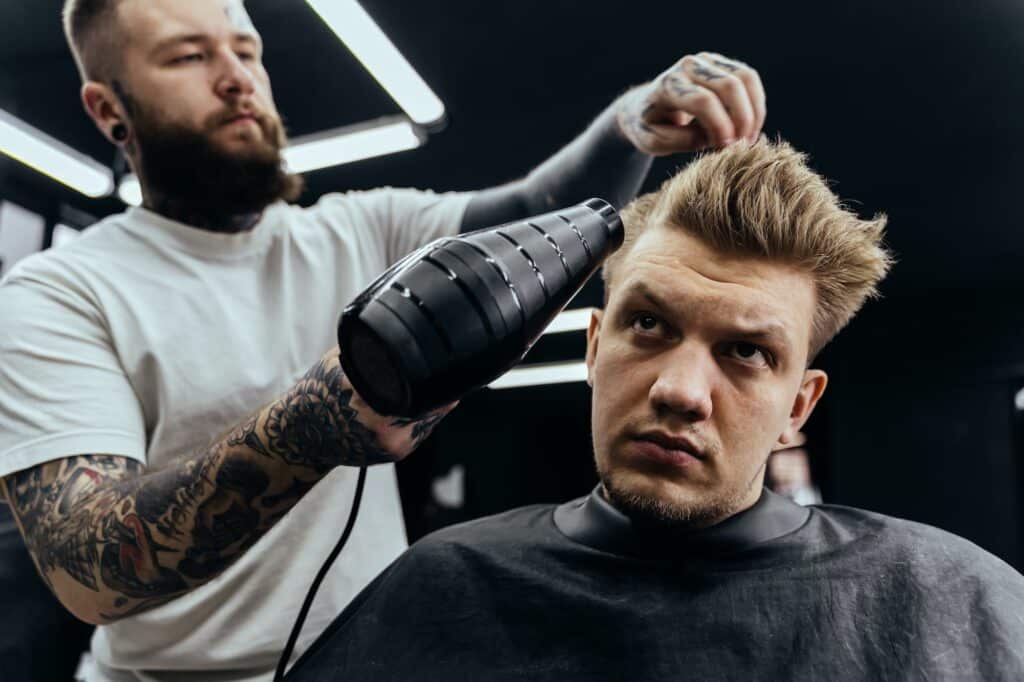 Un coiffeur sèche les cheveux d'un homme dans un salon de coiffure.